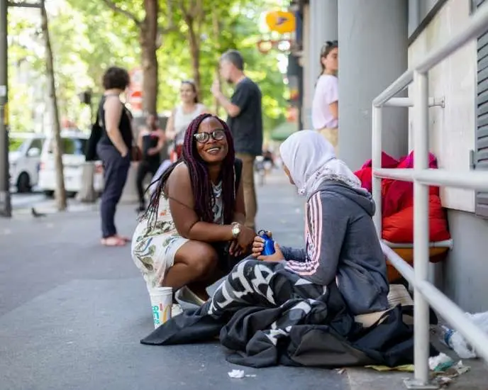 olunteer woman serving homemade soup and sandwiches to homeless individuals on the streets of Barcelona